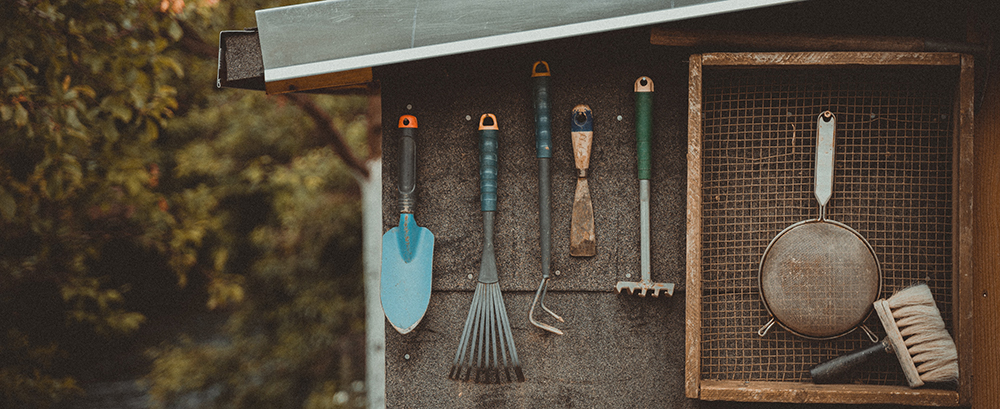 Gardening tools hang on the side of a shed